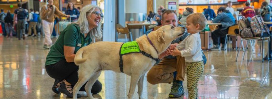 Travelers smiling and interacting with SEA Pup and Volunteer.