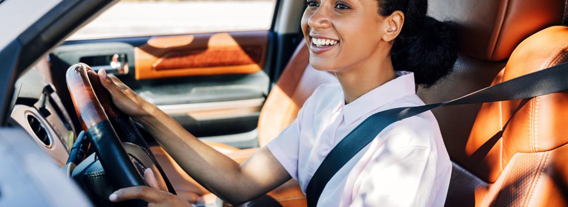 Woman in white shirt driving her car.
