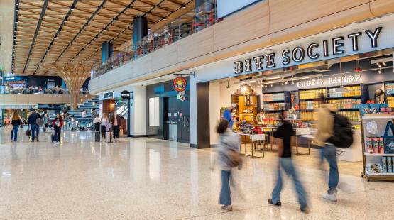 Travelers walk through the new C Concourse Expansion area in SEA Airport, with the Bite Society storefront shown in the background