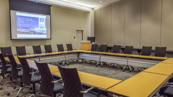 View from inside the Seoul Conference room showcasing a Hollow Square set for 24 people, the podium, and dropdown projector screen