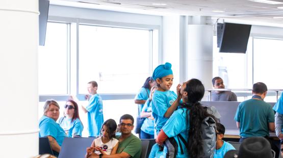 Parent and child in blue Wings for All shirts hug and smile in the gate area