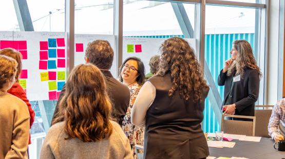 Group of participants gather around post it notes on a window. 