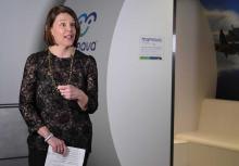 Commissioner Gregoire in front of a mother's nursing suite at Sea-Tac