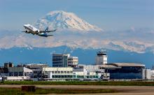 A view of Sea-Tac Airport looking southeast toward Mt. Rainier, as a jet takes off in the foreground.
