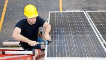 An electrician works on a solar panel ready for installation