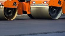 Road construction equipment rolls newly paved road