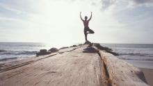 Woman doing yoga at the end of a pier