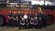 Stephanie McGinnis with her battalion in front of a red fire truck at the Port of Seattle fire department