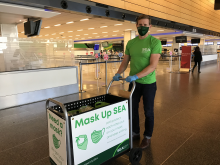 commissioner Ryan Calkins pushing the mask UP SEA cart wearing a green shirt