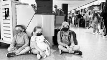 the Gaston family sits on the floor at SEA Airport waiting for their flight