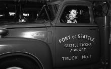 Historic black and white photo of Dalmatian sitting in Port of Seattle Fire Department fire truck