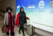 Passengers in masks carrying luggage through the terminal