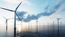 Offshore wind turbines against a sunset sky.