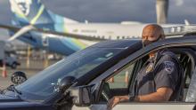 Police officer in uniform standing next to his police cruiser at SEA Airport April 2021