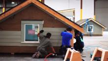 Youth participants in the Opportunity Youth Initiative install siding on a home's exterior