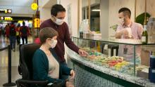 A couple chooses macaroons at a locally-owned shop in SEA Airport as a worker assists customers June 2021