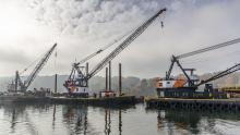 Floating cranes on the Duwamish River in misty air with fall colored bank behind 
