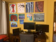 Desk with bright yellow wall and paintings hanging on the wall