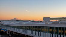 Southward, exterior view of the new International Arrivals Facility at SEA against an orange sunset silhouetting Mt Rainier 