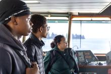 Three people look out the front of a WA State Ferry