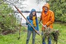 Two port staff members clean up park along the Duwamish with shovel 