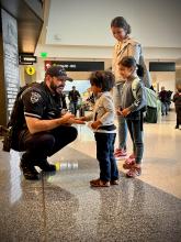 Police officer greeting two young children at the airport.