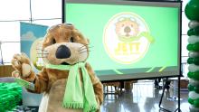 Photograph of costumed SEA Airport mascot Jett the SEA Otter, a sea otter with a green scarf and aviator goggles