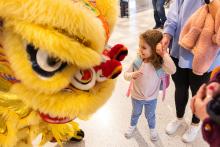 Lion dancer with a child smiling at them 