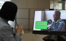 A customer in the terminal looking at a display screen that reads 'click to connect with Customer Care' and shows a happy customer service representative. 