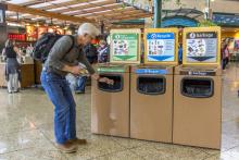 Man discards compost items at bin in an airport terminal.