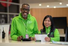 Two pathfinders airport employees at information booth smiling.