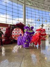 2025 Lunar New Year display in front of the window wall at central terminal. Includes two traditional dancers in red and purple costumes.